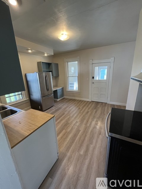 A kitchen with a black refrigerator and wooden floors.