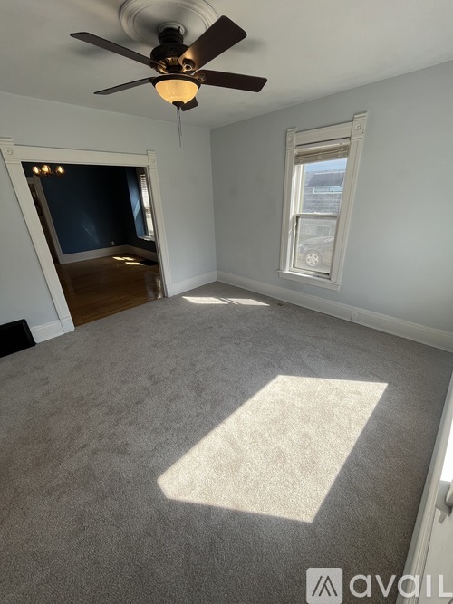 A room with a ceiling fan and carpeted floor.
