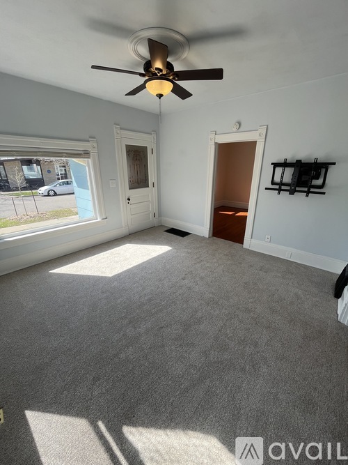 A room with a ceiling fan and carpeted floor.