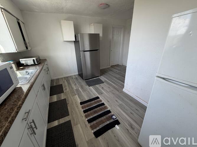 A kitchen with white cabinets and a refrigerator.
