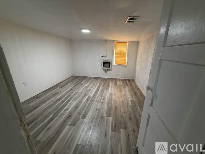A room with wooden flooring and a window with blinds.