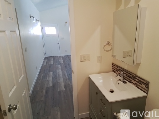 A bathroom with a sink, mirror, and wooden floors.