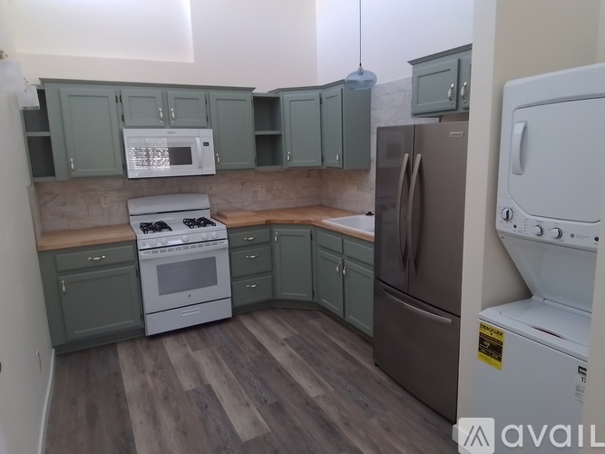A kitchen with green cabinets and a white microwave above the stove.