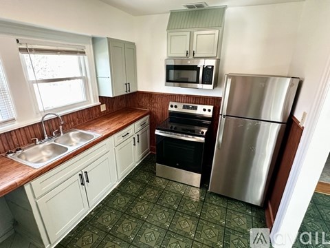A kitchen with a stove, sink, and refrigerator.