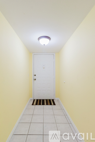 A hallway with a white door and tiled floor.