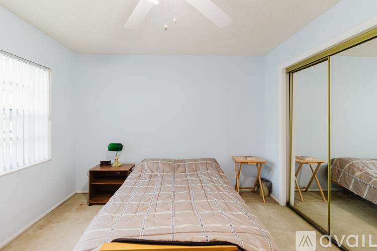 A bedroom with a bed, a ceiling fan, and a mirror.