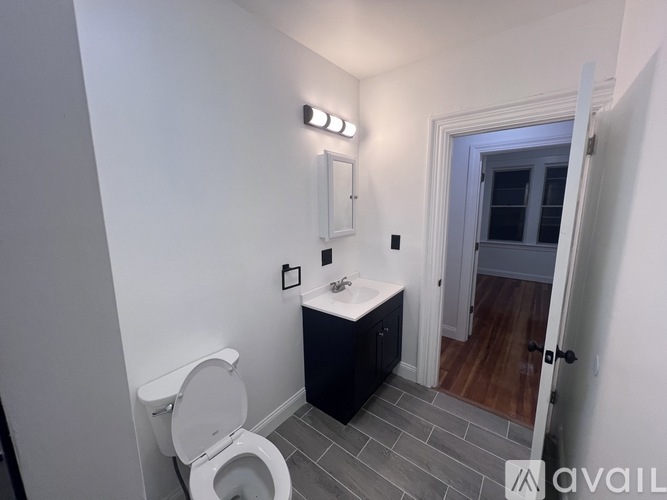 A bathroom with a toilet, sink, and light switches.