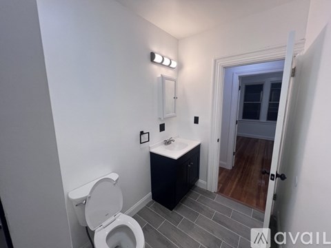 A bathroom with a toilet, sink, and light switches.