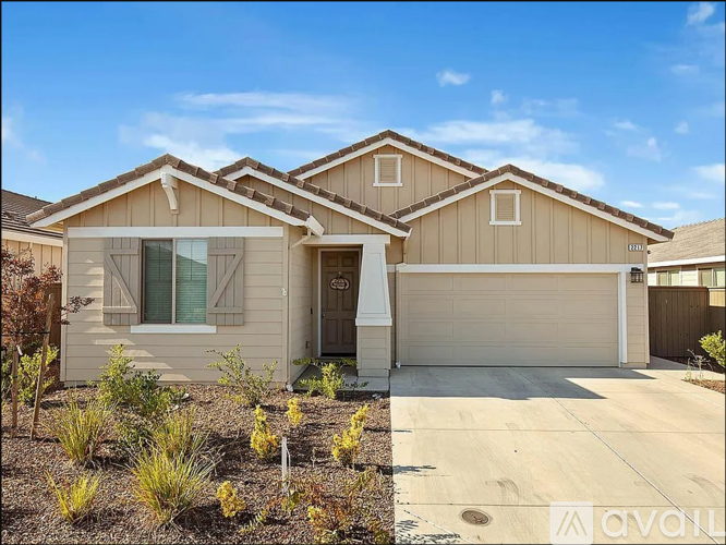 A beige house with a garage door and a driveway.