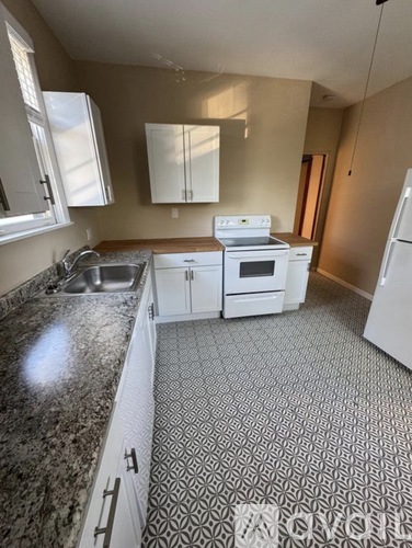 A kitchen with a white fridge, white oven, and white cabinets.
