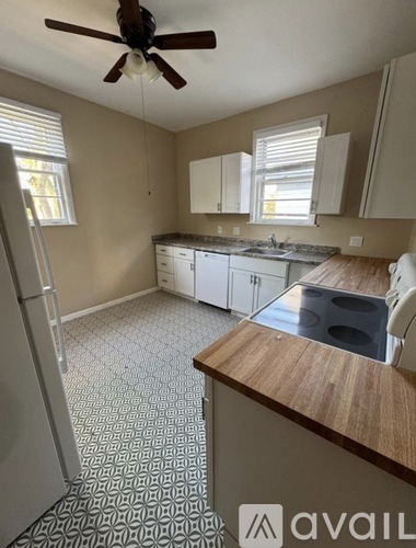 A kitchen with a refrigerator, sink, and cabinets.