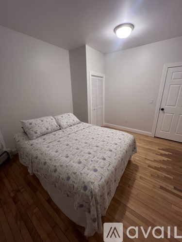 A bedroom with a bed and wooden floors.
