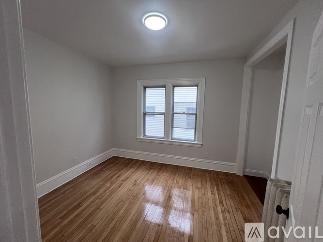 A room with wooden flooring and a window with blinds.