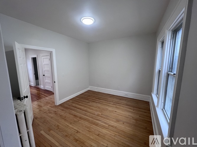 A room with wooden flooring and a window on the right side.