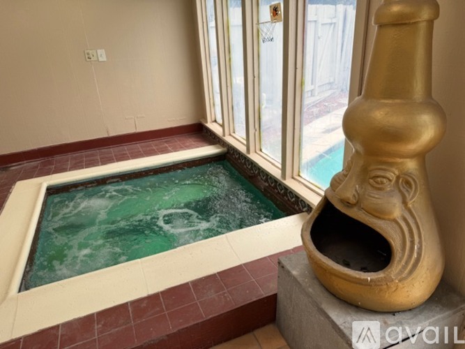 A hot tub in a room with a window and a sculpture.