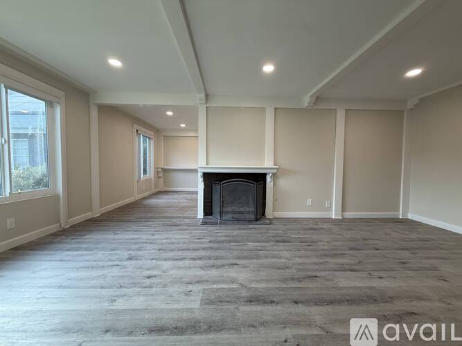 A spacious living room with a fireplace and a carpeted floor.