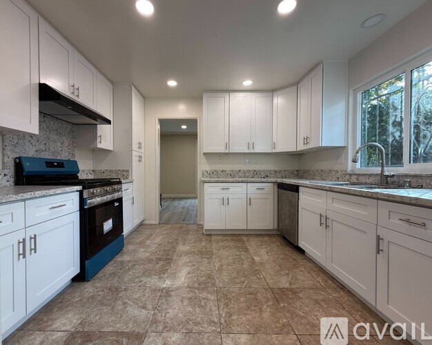 A kitchen with white cabinets and a tiled floor.