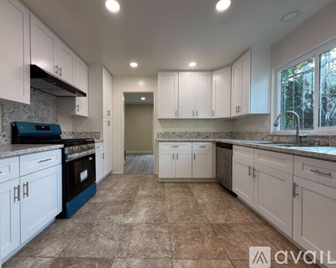 A kitchen with white cabinets and a tiled floor.