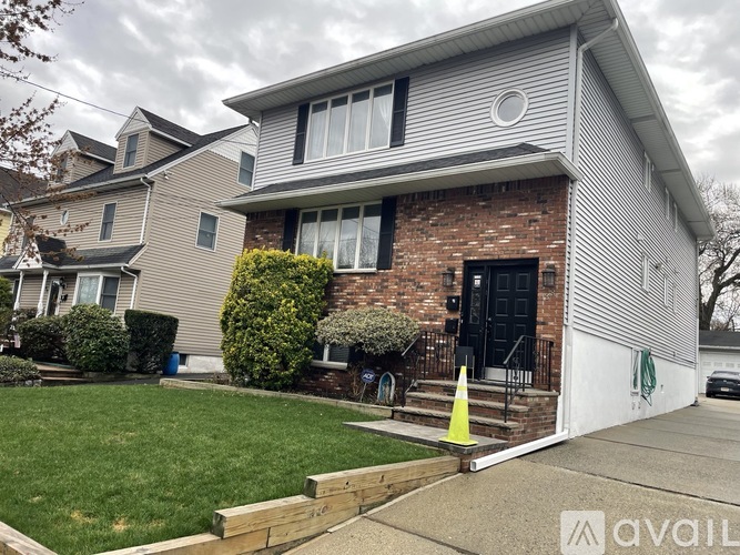 A house with a grey siding and a black door is for sale.
