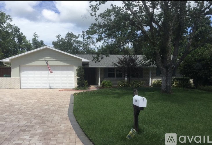 A house with a white garage door and a brick driveway.