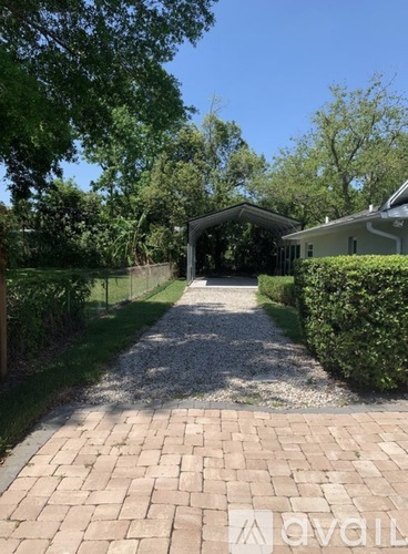 A gravel pathway leads to a house with a covered patio.
