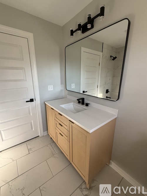A bathroom with a sink, mirror, and wooden cabinet.