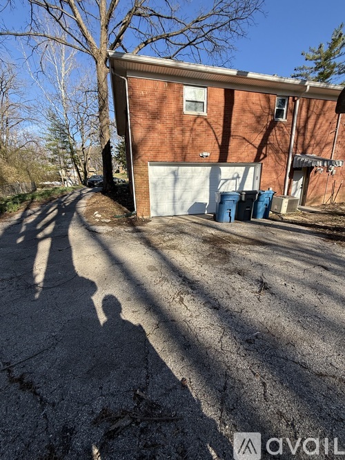 A shadow of a person is cast on a cracked driveway in front of a brick building.