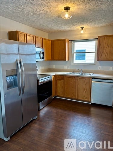 A kitchen with wooden cabinets and a stainless steel refrigerator.