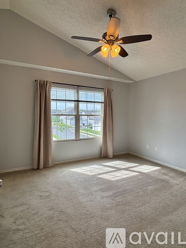 A room with a ceiling fan and a window with curtains.