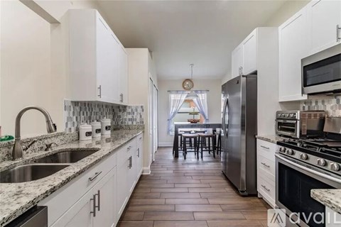 A kitchen with white cabinets and a black refrigerator.
