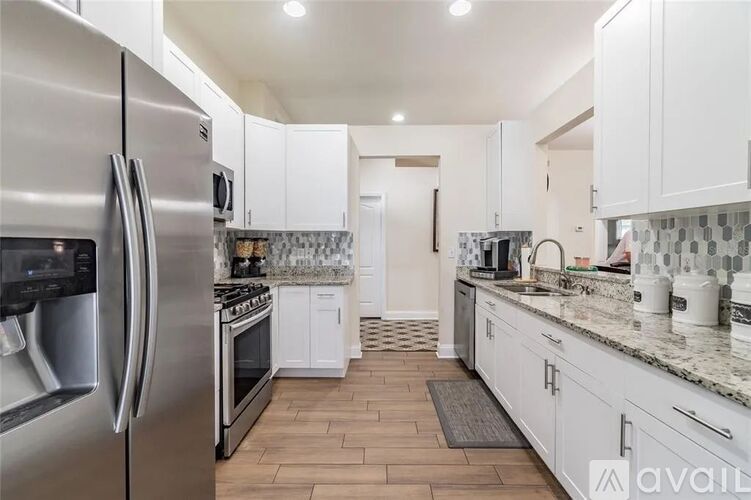 A kitchen with white cabinets and a stainless steel refrigerator.