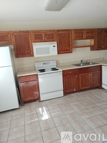 A kitchen with white appliances and wooden cabinets.