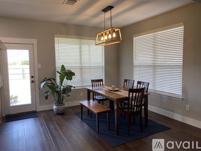 A dining room with a table set for four and a potted plant.