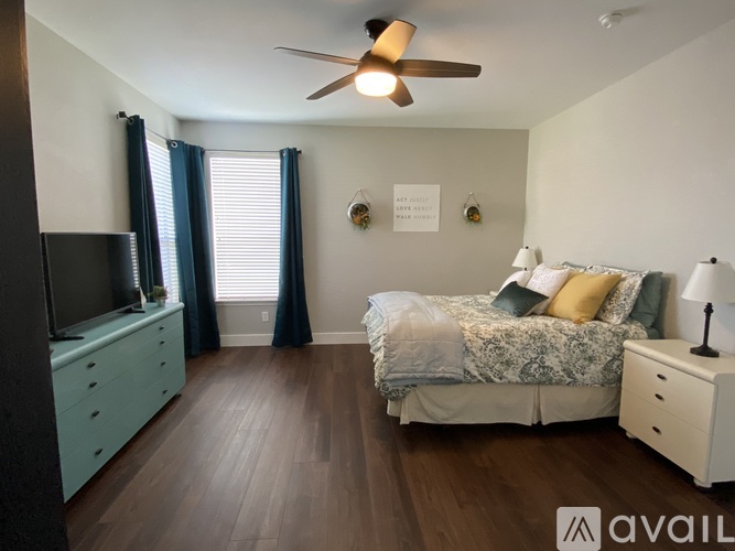 A bedroom with a bed, dresser, and ceiling fan.