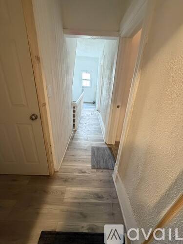 A hallway with a rug on the floor and a door on the left.