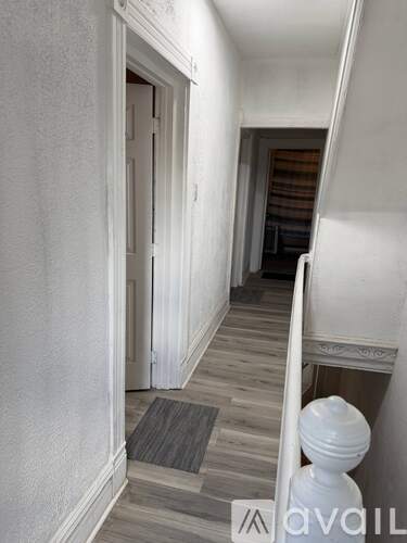 A hallway with a white door and a grey carpet.