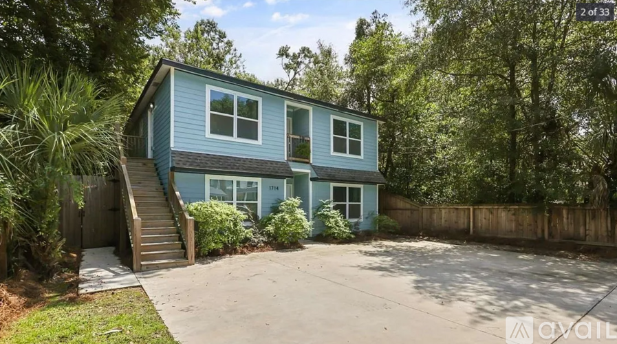 A blue house with a wooden fence and a driveway in front.