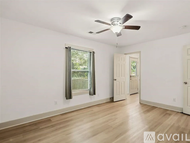 A spacious room with a ceiling fan and wooden flooring.