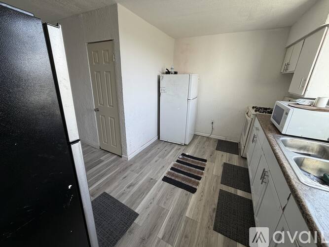 A kitchen with a white fridge, white cabinets, and a white stove top oven.
