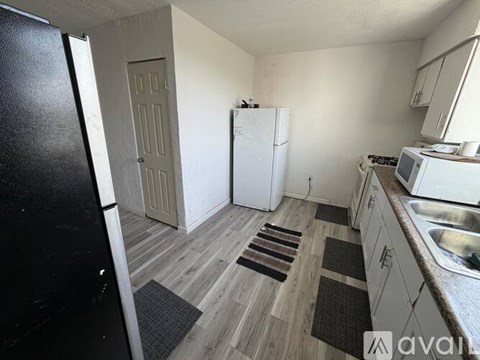 A kitchen with a white fridge, white cabinets, and a white stove top oven.