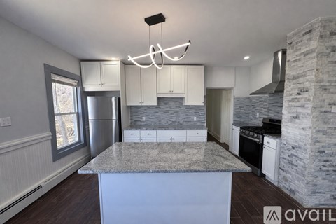 A kitchen with a marble island and a stone pillar.