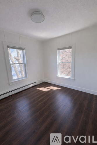 A room with wooden floors and two windows.