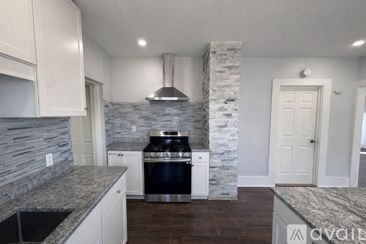 A modern kitchen with a stone backsplash and a stainless steel range hood.