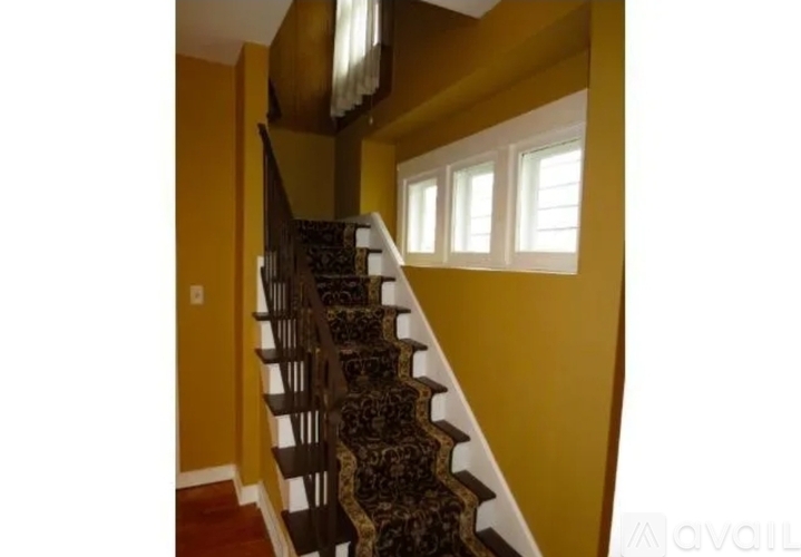 A staircase with a black and white patterned carpet.