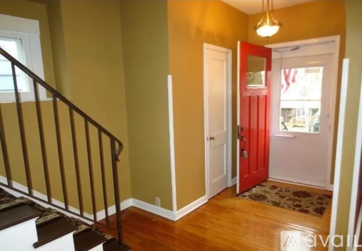 A hallway with a red door and a staircase.