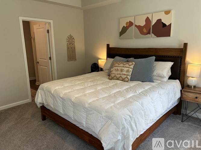 A bedroom with a large bed and a painting on the wall.