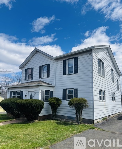 A two-story house with a white exterior and black shutters.