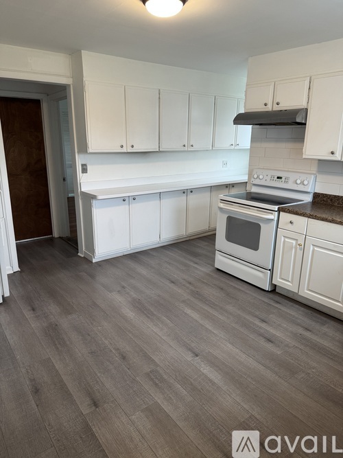 A kitchen with white cabinets and a stove top oven.