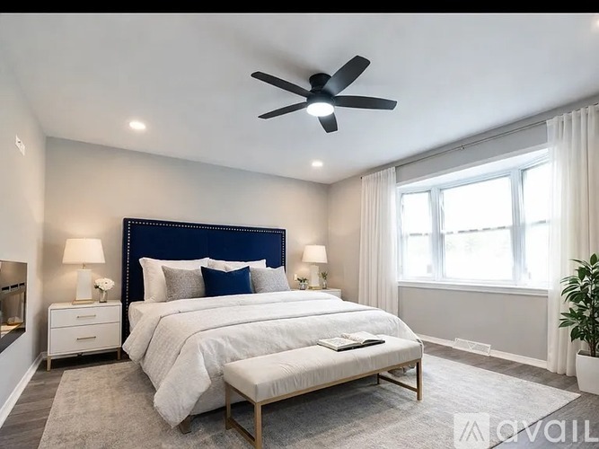 A bedroom with a large bed and a ceiling fan.