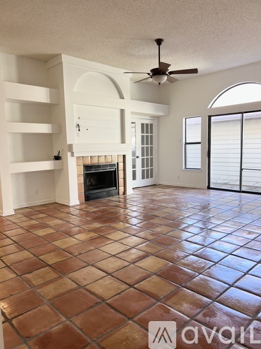 A living room with a fireplace and a fan.